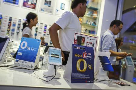 People walk inside a mobile phone shop at a department store in Bangkok in this April 13, 2014 file photo. REUTERS/Athit Perawongmetha/Files