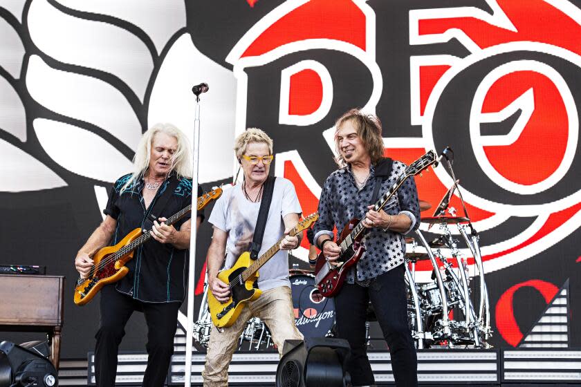 Bruce Hall, Kevin Cronin and Dave Amato of REO Speedwagon peform on an outdoor stage