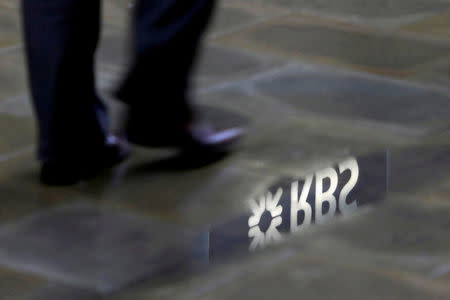 FILE PHOTO: A man walks past a Royal Bank of Scotland branch logo reflected in a puddle in London, Britain, January 14, 2010. REUTERS/Stefan Wermuth/File Photo