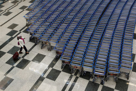 FILE PHOTO: A woman prepares to take a trolley as she arrives at Terminal 3 of Singapore's Changi Airport August 20, 2013. REUTERS/Edgar Su/File Photo