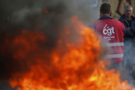 A striking French CGT labour union employee stands near a barricade to block the entrance of the depot of the SFDM company near the oil refinery to protest the the governments proposed labor law reforms in Donges, France, May 26, 2016. REUTERS/Stephane Mahe