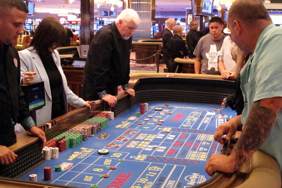 In this June 20, 2019 photo, players gather around a table for a game of craps at the Hard Rock casino in Atlantic City N.J. New Jersey's casinos won nearly $3.3 billion from gamblers in 2019, the first time since 2012 that the Atlantic City gambling halls had won more than $3 billion, according to figures released Tuesday, Jan. 14, 2020, by the New Jersey Division of Gaming Enforcement. (AP Photo/Wayne Parry)