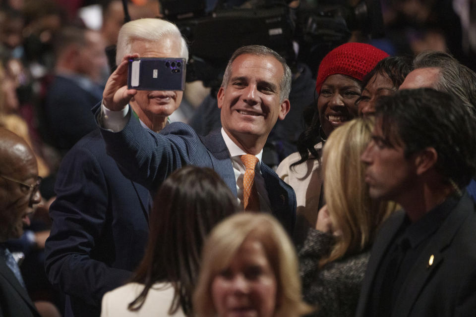 Outgoing Los Angeles Mayor Eric Garcetti, middle, and former California Gov. Gray Davis, left, take selfie photos at the inauguration ceremony for Karen Bass, the first Black woman elected Los Angeles mayor, in Los Angeles Sunday, Dec. 11, 2022. (AP Photo/Damian Dovarganes)