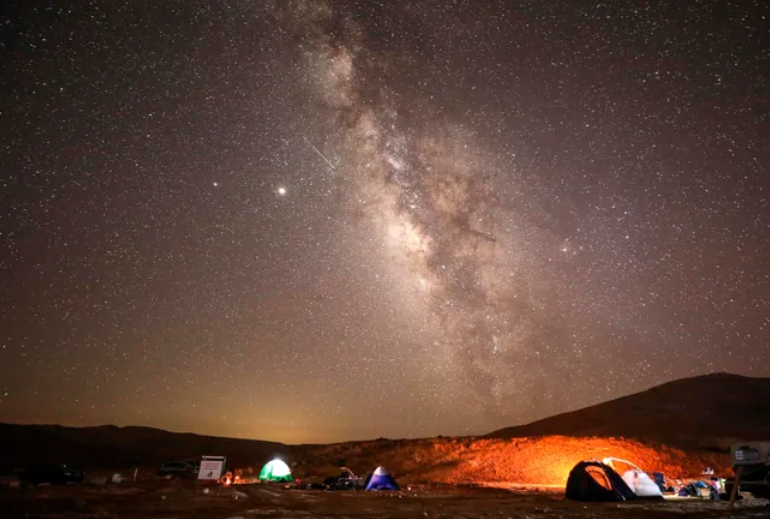 A Perseid meteor streaks across the sky above a campsite in the Negev desert, near the city of Mitzie Ramon in Israel on Aug. 11, 2020. The Perseids become visible during mid-August.