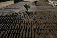 Cristian, center, turns clay bricks on their sides as they sun dry before they are put in a kiln at a small brick factory in Tobati, Paraguay, Monday, Aug. 24, 2020. While the government prohibits minors under 14 from working at brick factories, the 11-year-old said he's been working here to compliment his family's income, even before COVID-19 pandemic closed schools. (AP Photo/Jorge Saenz)