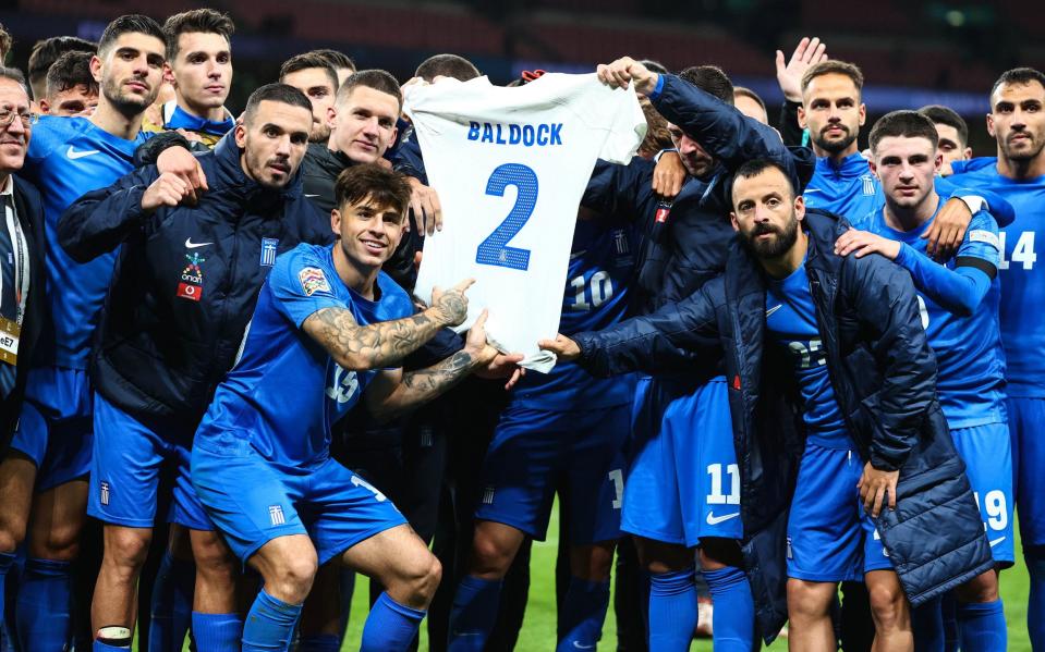 The Greece players hold up George Baldock's shirt