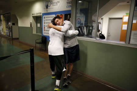 Runners from the Midnight Mission Running Club, Seth Becker, 22, (R) and Oscar Knight, 53, greet each other before beginning a sunrise run through Skid Row in Los Angeles, California April 20, 2015. REUTERS/Lucy Nicholson