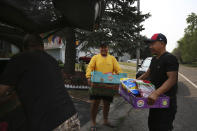 Jalue Dorje, center, helps load a car with food that was blessed during a ceremony honoring Guru Rinpoche, the Indian Buddhist master who brought Tantric Buddhism to Tibet, on Tuesday, July 20, 2021, in Columbia Heights, Minn. The food was donated to families across the Minneapolis suburbs. (AP Photo/Jessie Wardarski)