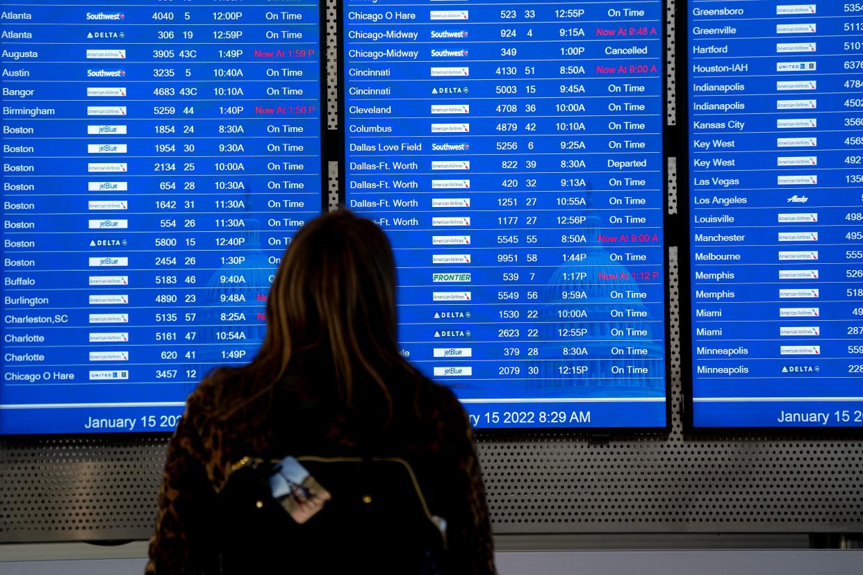 A traveler checks flight schedules for various airlines at Ronald Reagan Washington National Airport (DCA) in Arlington, Virginia, on January 15, 2022. (Photo by Stefani Reynolds / AFP)
