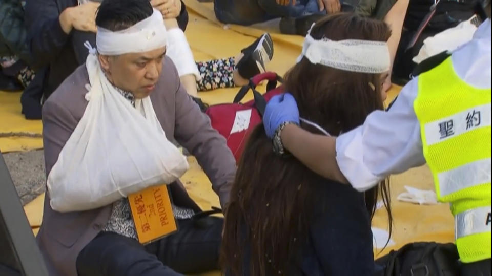 This image made from video shows the survivors of a bus accident are treated on the roadside in Hong Kong, Wednesday, Dec. 18, 2019. The crash of a double-decker bus in Hong Kong killed multiple people, emergency services said. (TVB via AP)