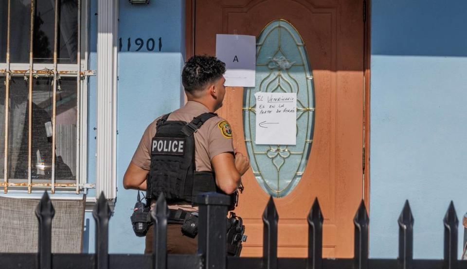 A police officer reads a sign at the front of a house located at 11901 SW 185th Terrace Saturday, Jan. 27, 2024. The sign is written in Spanish and tells people to go to the back of the house for veterinary services. Police say the owner of the home was operating an unlicensed veterinary clinic. Pedro Portal/pportal@miamiherald.com