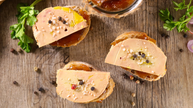 Foie gras on toast on wooden surface