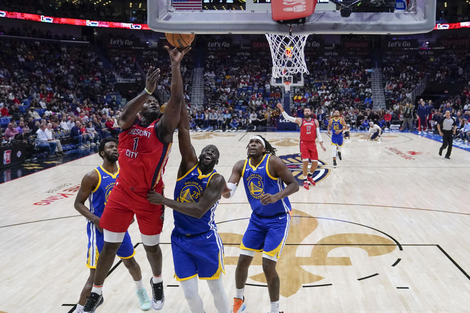 New Orleans Pelicans forward Zion Williamson (1) drives to the basket against Golden State Warriors forward Draymond Green (23) and forward Kevon Looney (5) in the first half of an NBA basketball game in New Orleans, Monday, Oct. 30, 2023. (AP Photo/Gerald Herbert)