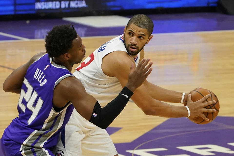 Los Angeles Clippers forward Nicolas Batum, right, looks to pass against Sacramento Kings guard Buddy Hield during the first quarter of an NBA basketball game in Sacramento, Calif., Friday, Jan. 15, 2021. (AP Photo/Rich Pedroncelli)