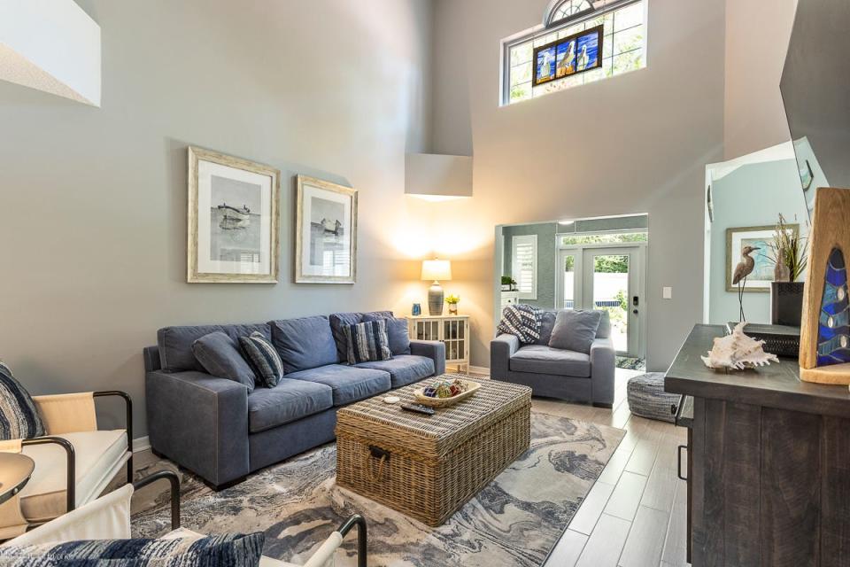 Extra light seeps into this beautifully designed great room, topped by extra high ceilings and covered in plank-tile flooring.