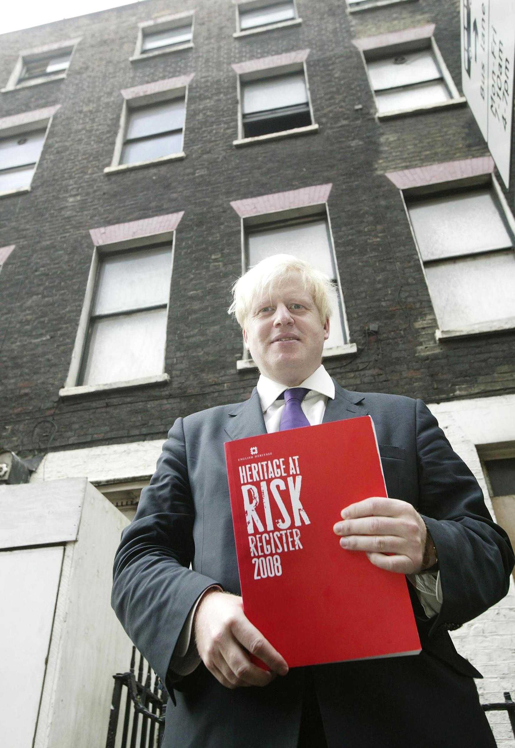 London Mayor Boris Johnson, with the Heritage At Risk Register outside 65 Swinton St, London, WC1, a grade ll listed building on the Heritage At Risk register.
