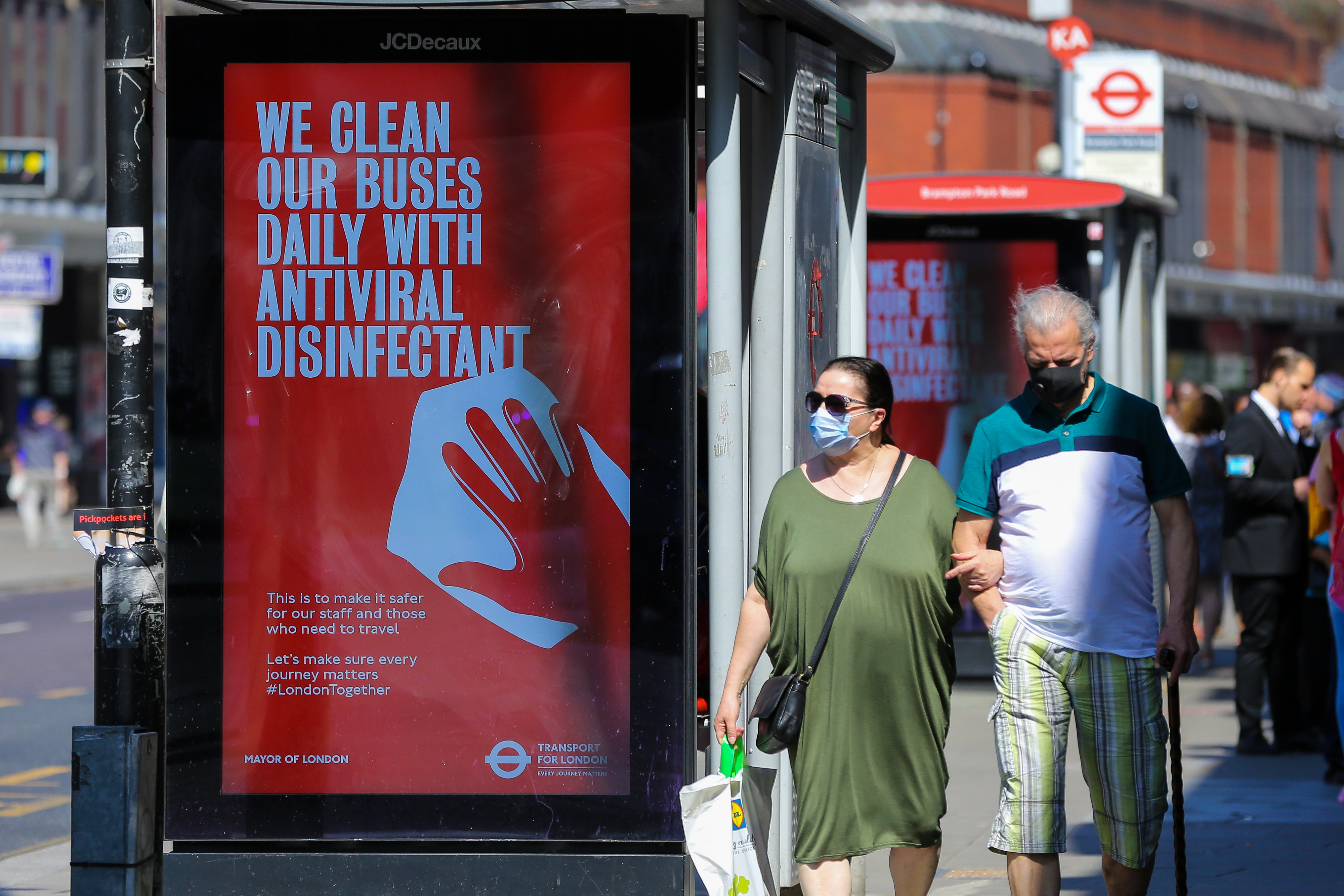 A couple wearing face masks as a preventive measure walk past 'We Clean Our Buses Daily With Antiviral Disinfectant' a Transport for London's digital COVID-19 campaign, in London. (Photo by Dinendra Haria / SOPA Images/Sipa USA)