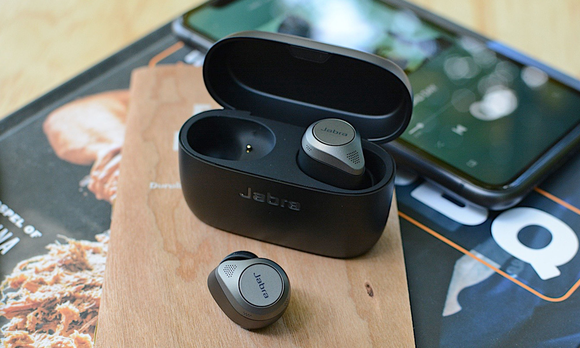 Jabra Elite 85t earbuds sitting on a few books.