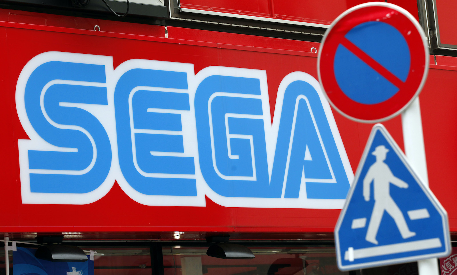A Sega Corp signboard is seen behind traffic signs at the Akihabara electronic store district in Tokyo June 19, 2011. Japanese video game developer Sega Corp said on Sunday that information belonging to 1.3 million customers has been stolen from its database, the latest in a rash of global cyber attacks against video game companies.     REUTERS/Kim Kyung-Hoon (JAPAN - Tags: CRIME LAW SCI TECH BUSINESS) - GM1E76J1BSN01