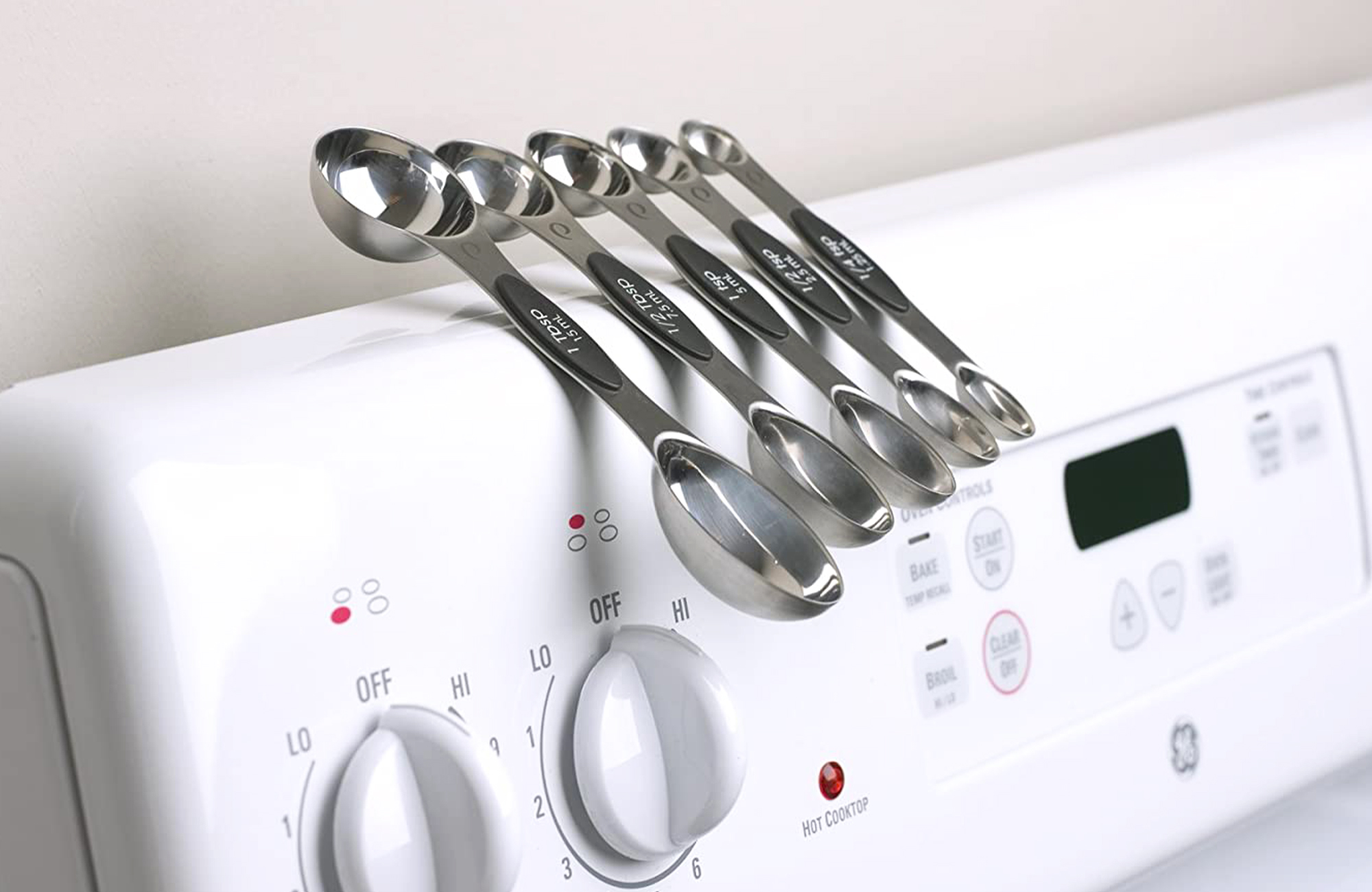 Magnetic measuring spoons stuck to a stove.