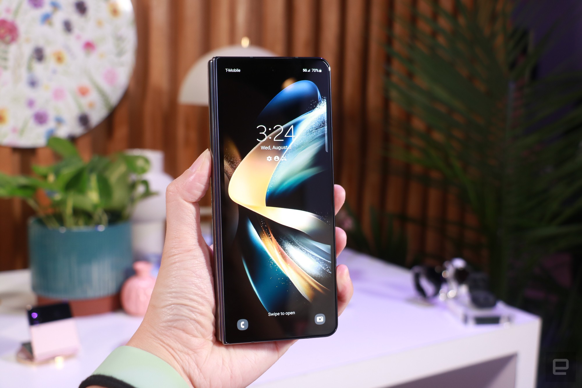 一只手举着封闭的 Galaxy Z Fold 4，其外部显示屏面向相机。