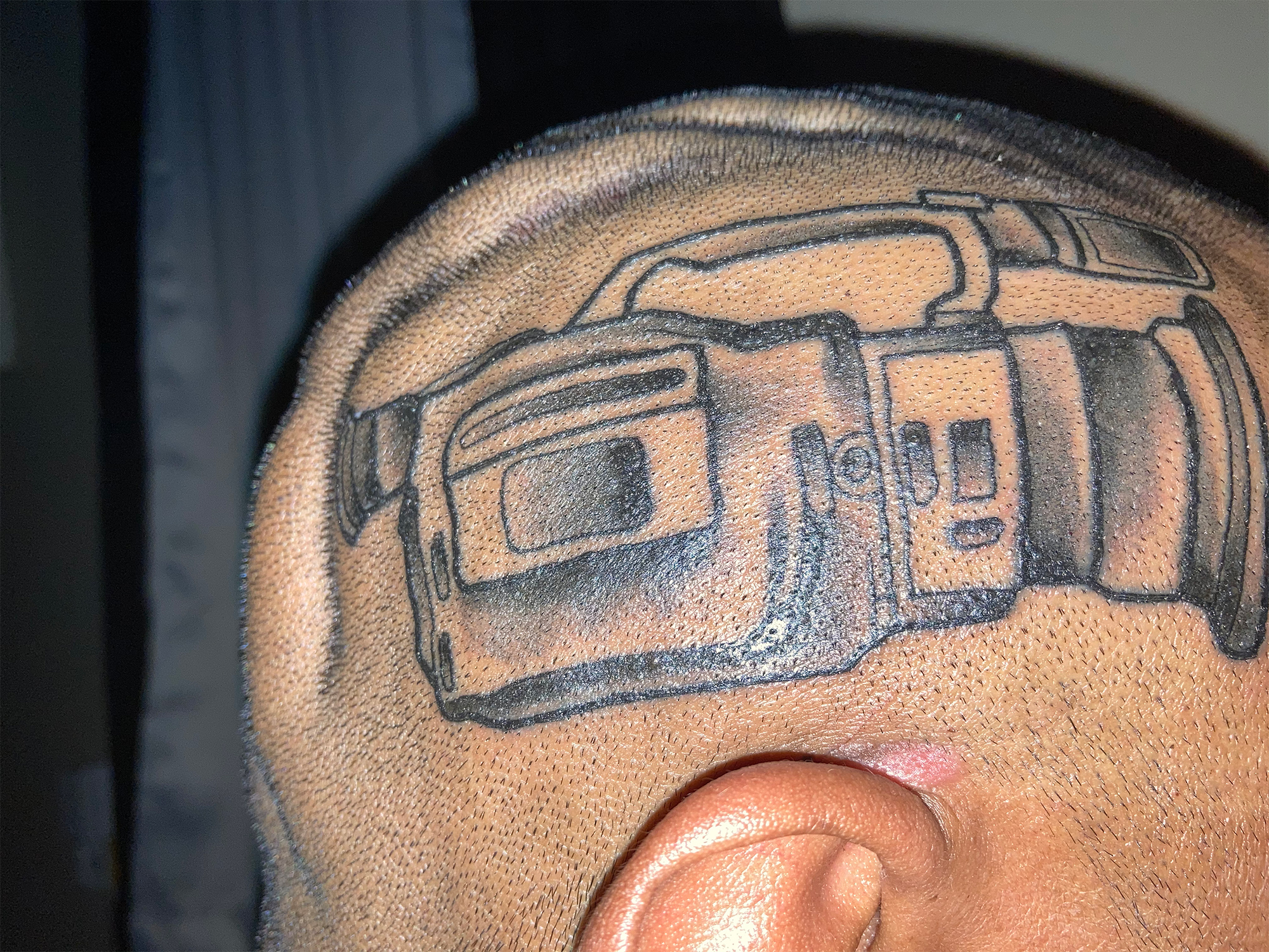 A man with a tattoo of the Sony VX1000 video camera on his head." data-uuid="051ab7bf-a43e-316b-a941-34f86e5d3151