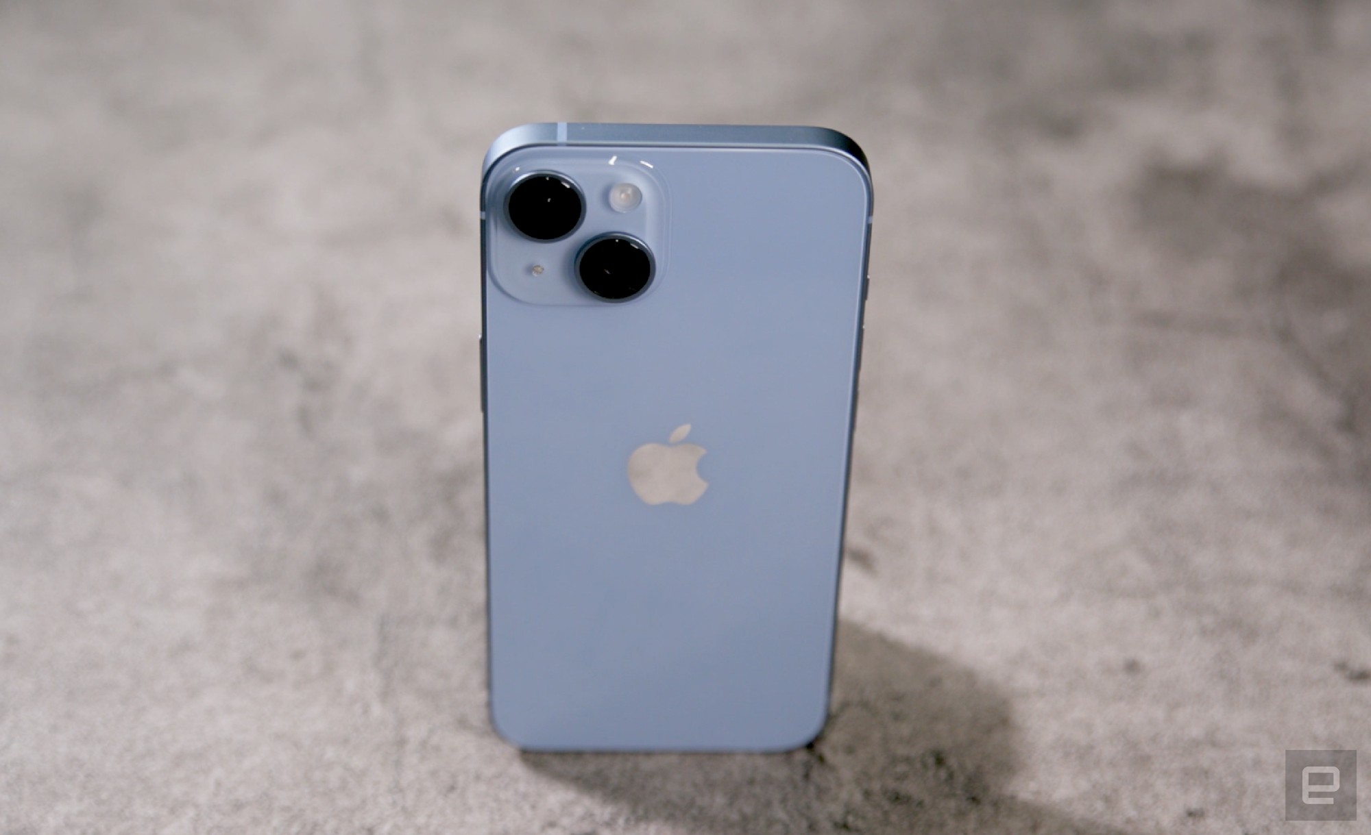 A slightly top down shot of the blue iPhone 14 standing with its rear cameras facing out.