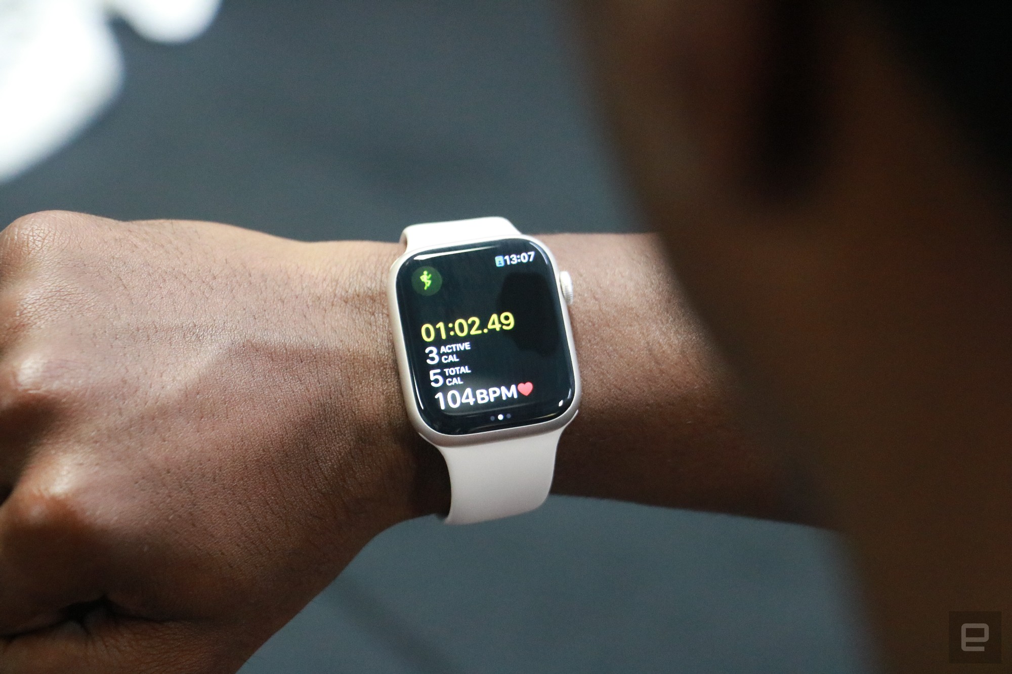 The Apple Watch Series 8 showing a workout tracking screen, on the wrist of a person looking at their watch in a gym.