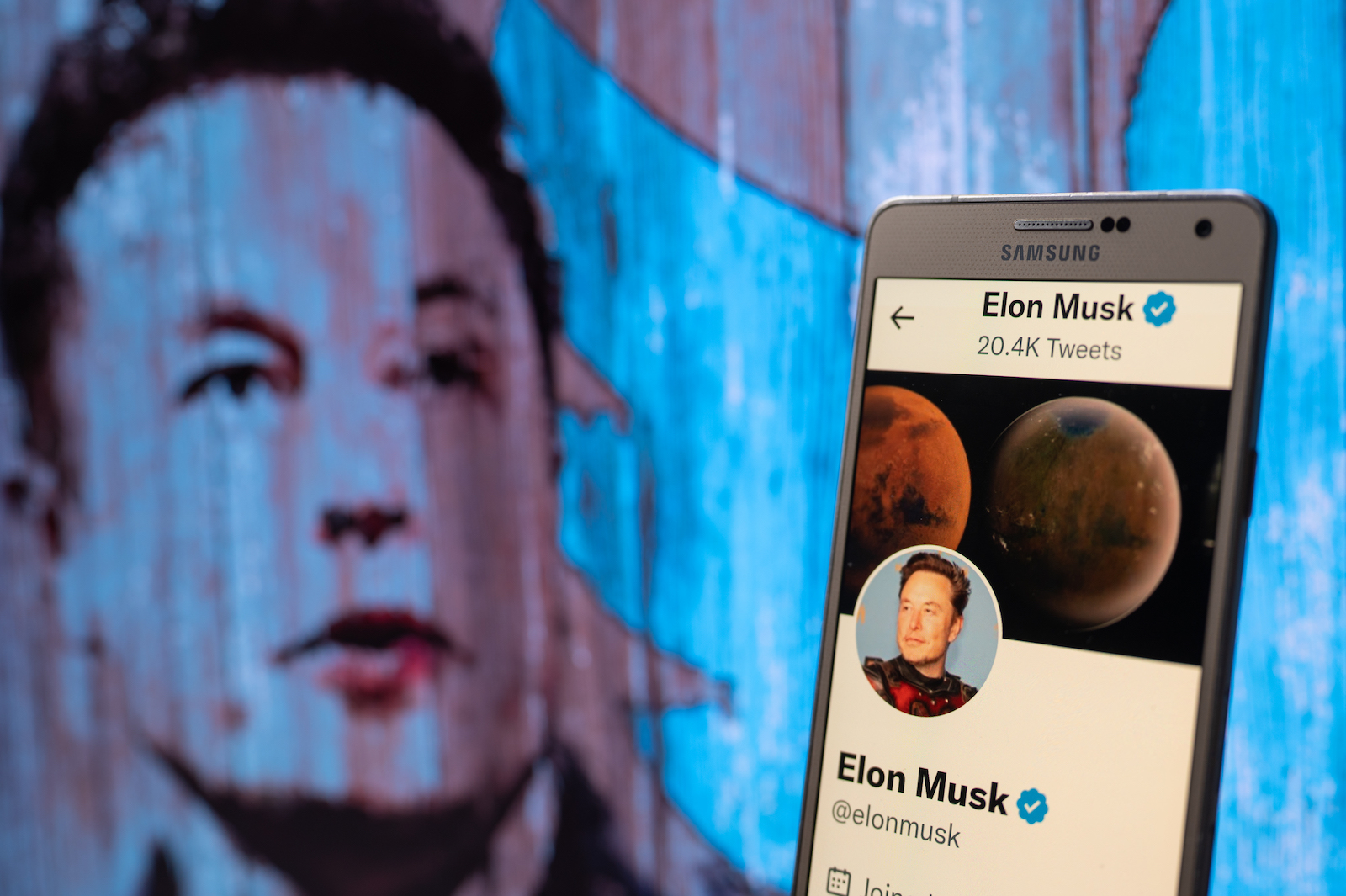Elon Musk's Twitter account displayed on a mobile with Elon Musk in the background are seen in this illustration. In Brussels - Belgium on 19 November 2022.  (Photo illustration by Jonathan Raa/NurPhoto)