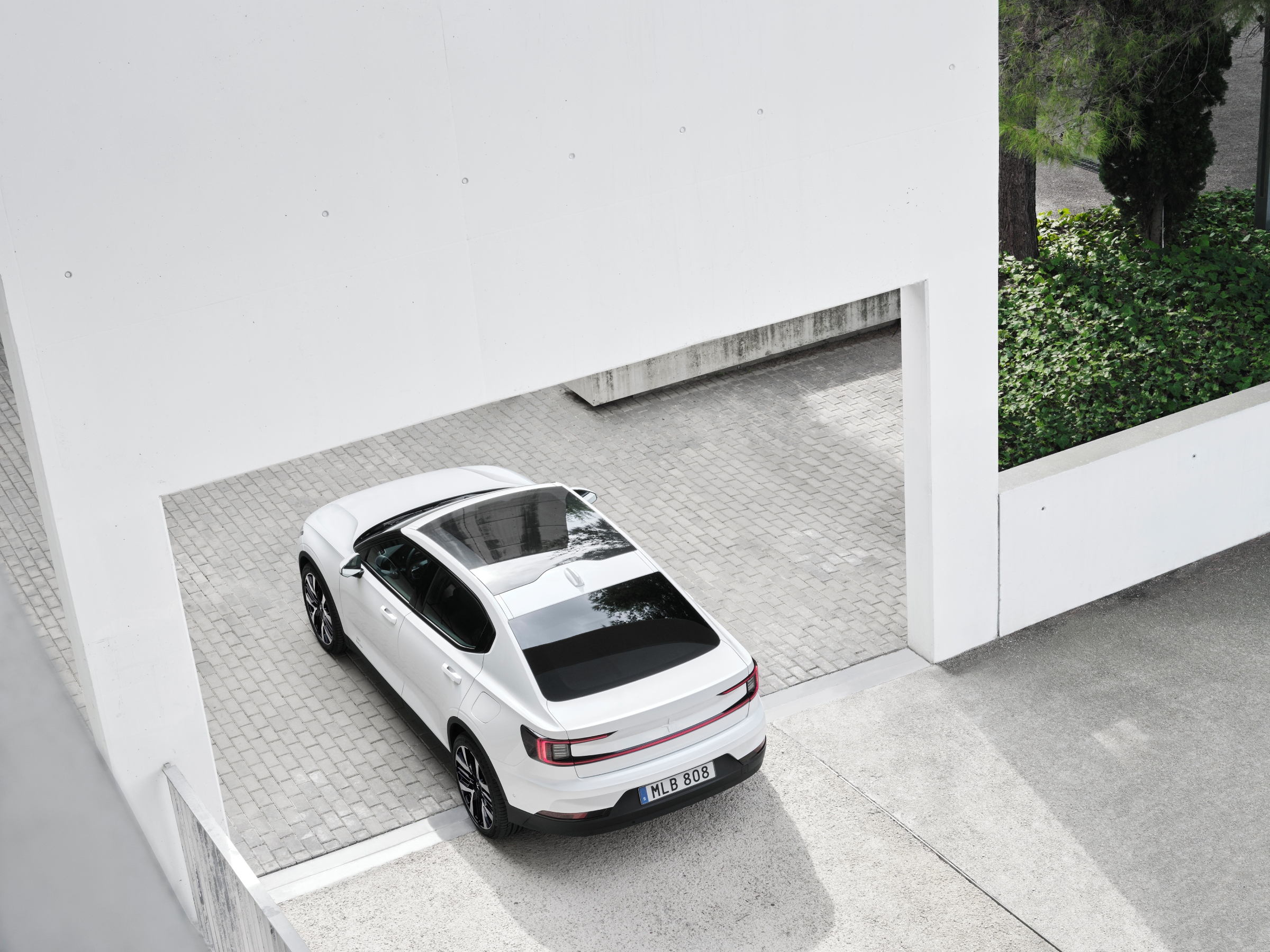 a white PS2 seen from above and to the left, sitting under a white arched wall 