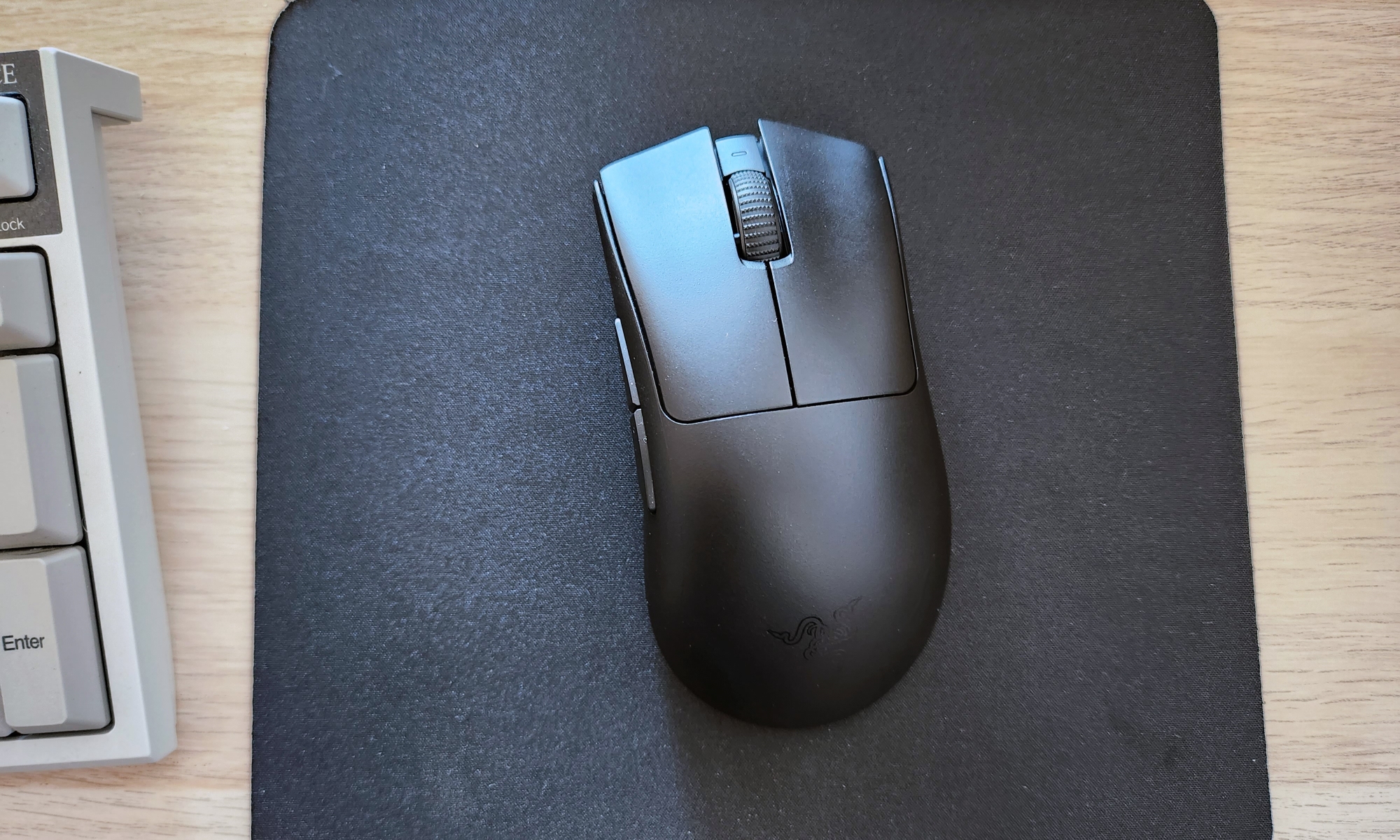 The Razer DeathAdder V3 Pro gaming mouse rested atop a black mouse pad on a desk.