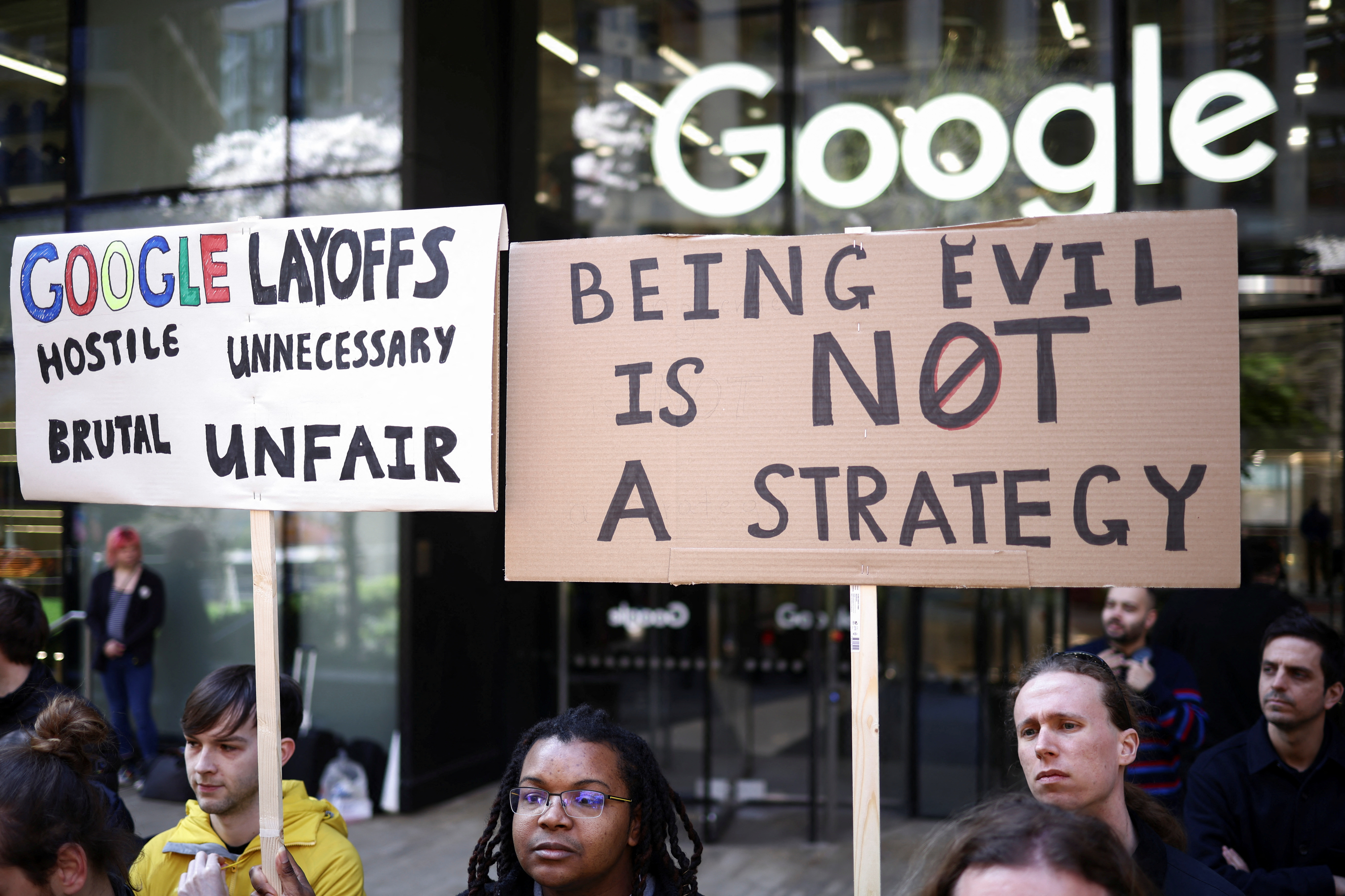 Google workers hold signs, including a reference to the company's 