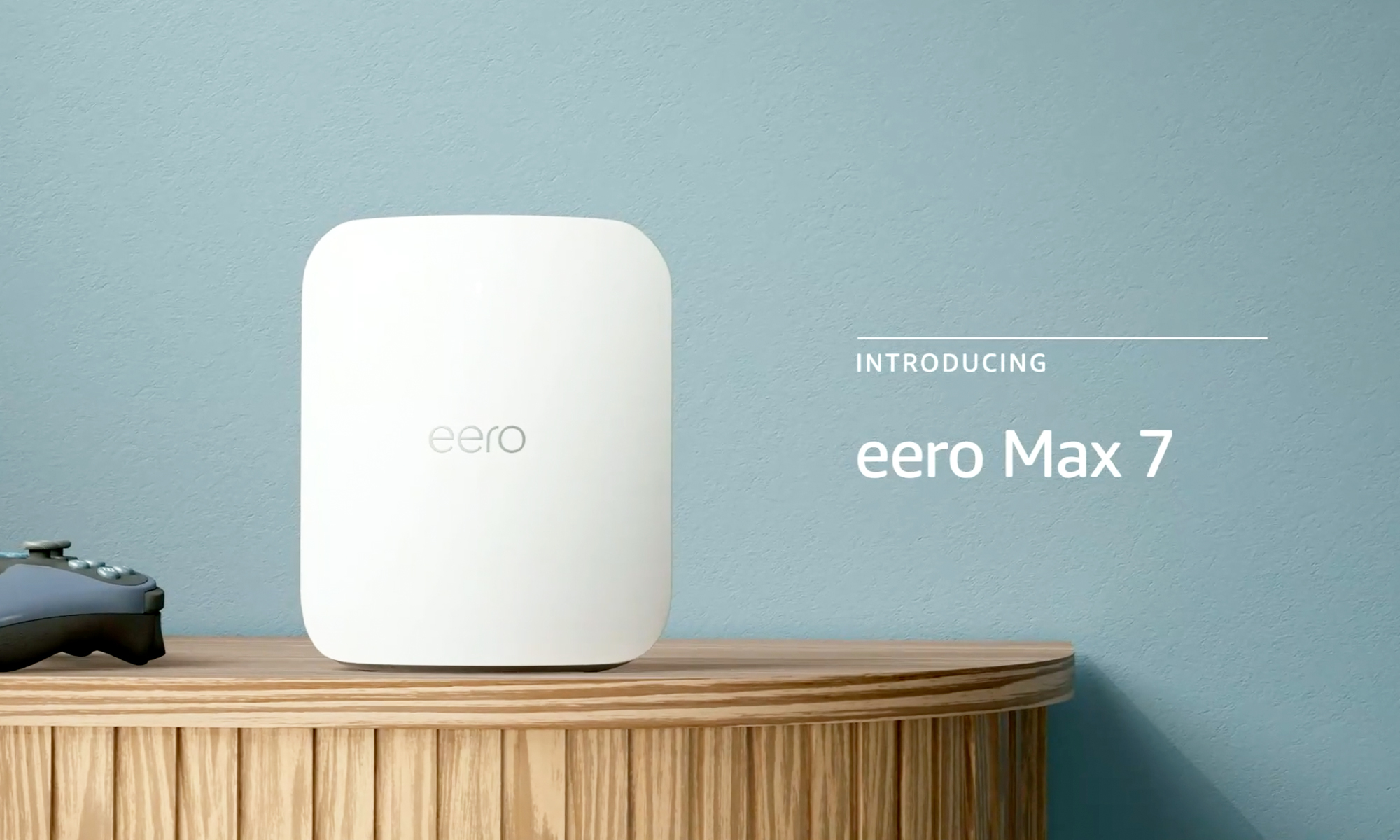 Amazon product photo of the Eero Max 7 Wi-Fi router. It sits on a stand next to a gaming controller. The superimposed text 