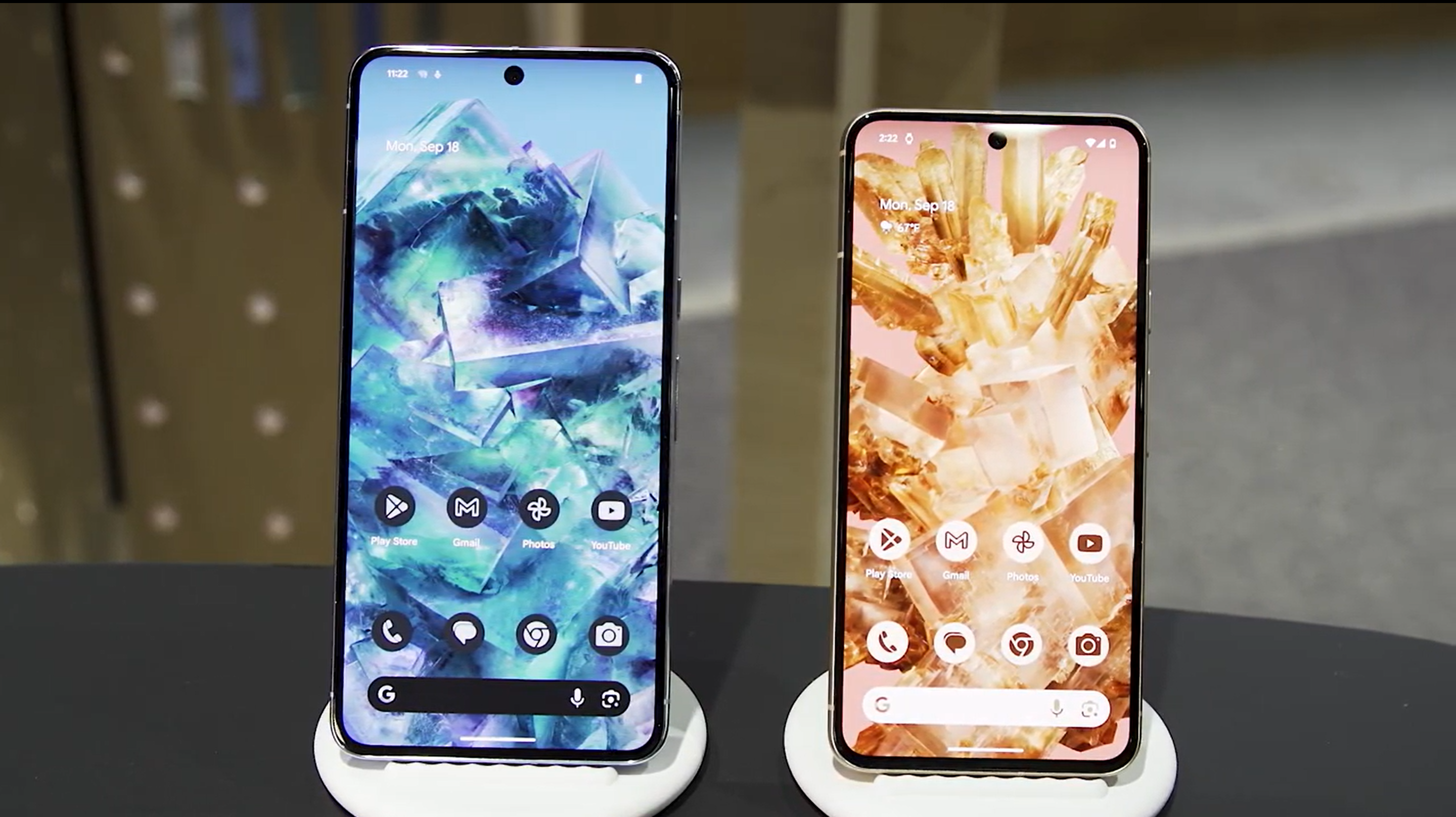 The Pixel 8 Pro and Pixel 8 on white stands on a desk with their screens facing out.