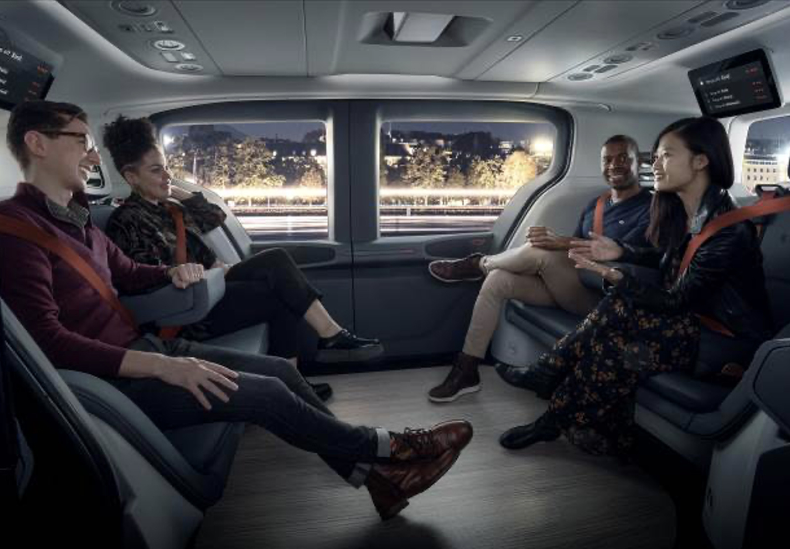 A vehicle cabin with four passengers sitting on opposite benches, facing each other. 