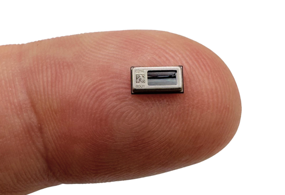 A small MEMS headphone driver is pictured on the tip of a finger.