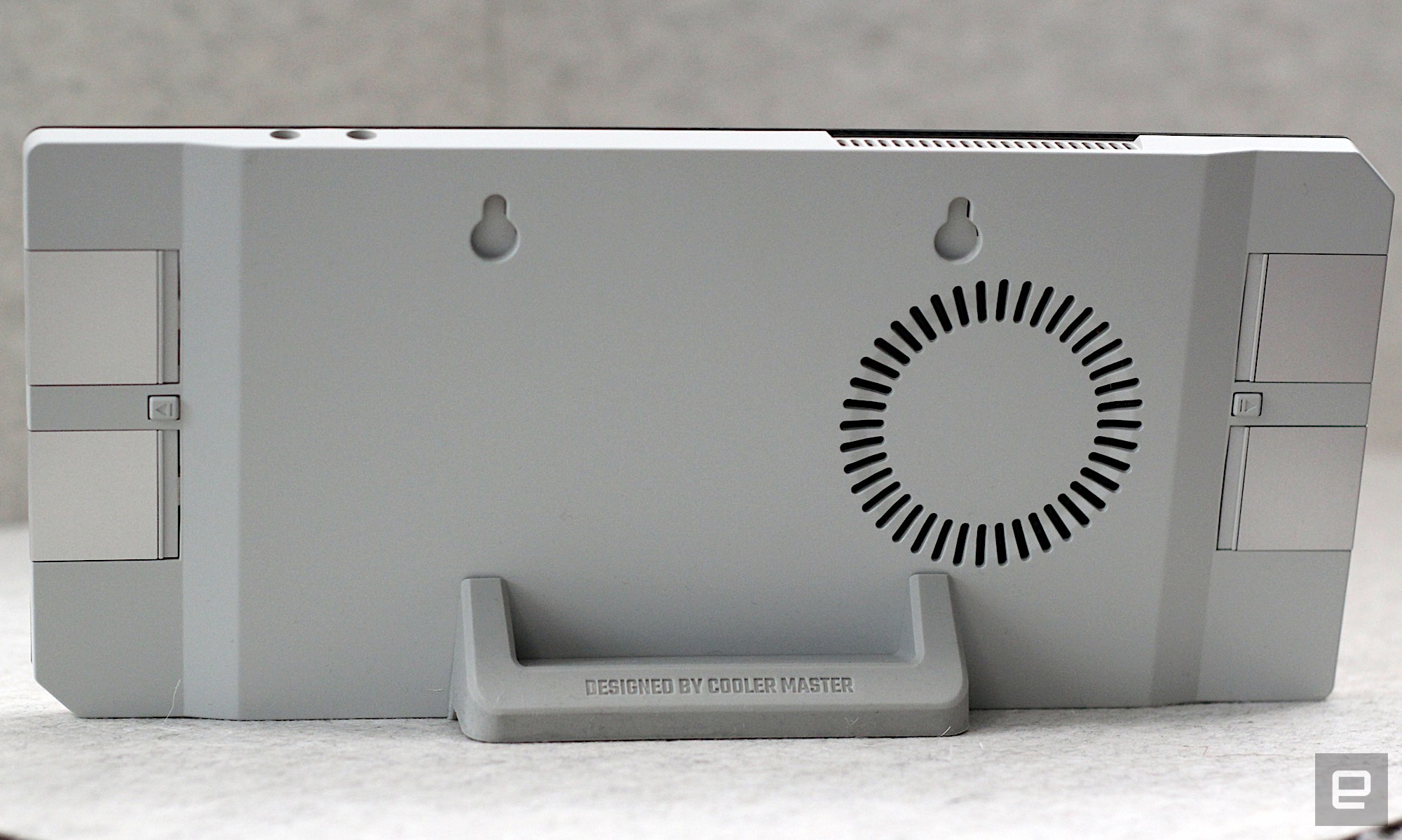 Image of the rear of the case, with the expansion cards visible. The case is on a grey cloth in front of a grey background, and the rear of the case is white.