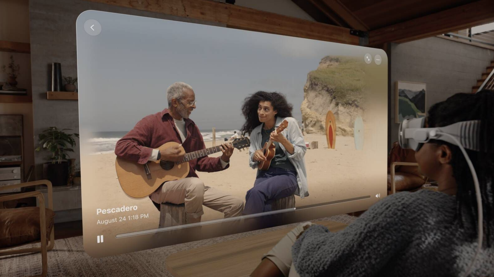 A lady wearing a Vision Reality Pro headset watching a memory from her couch of a guy playing guitar. 