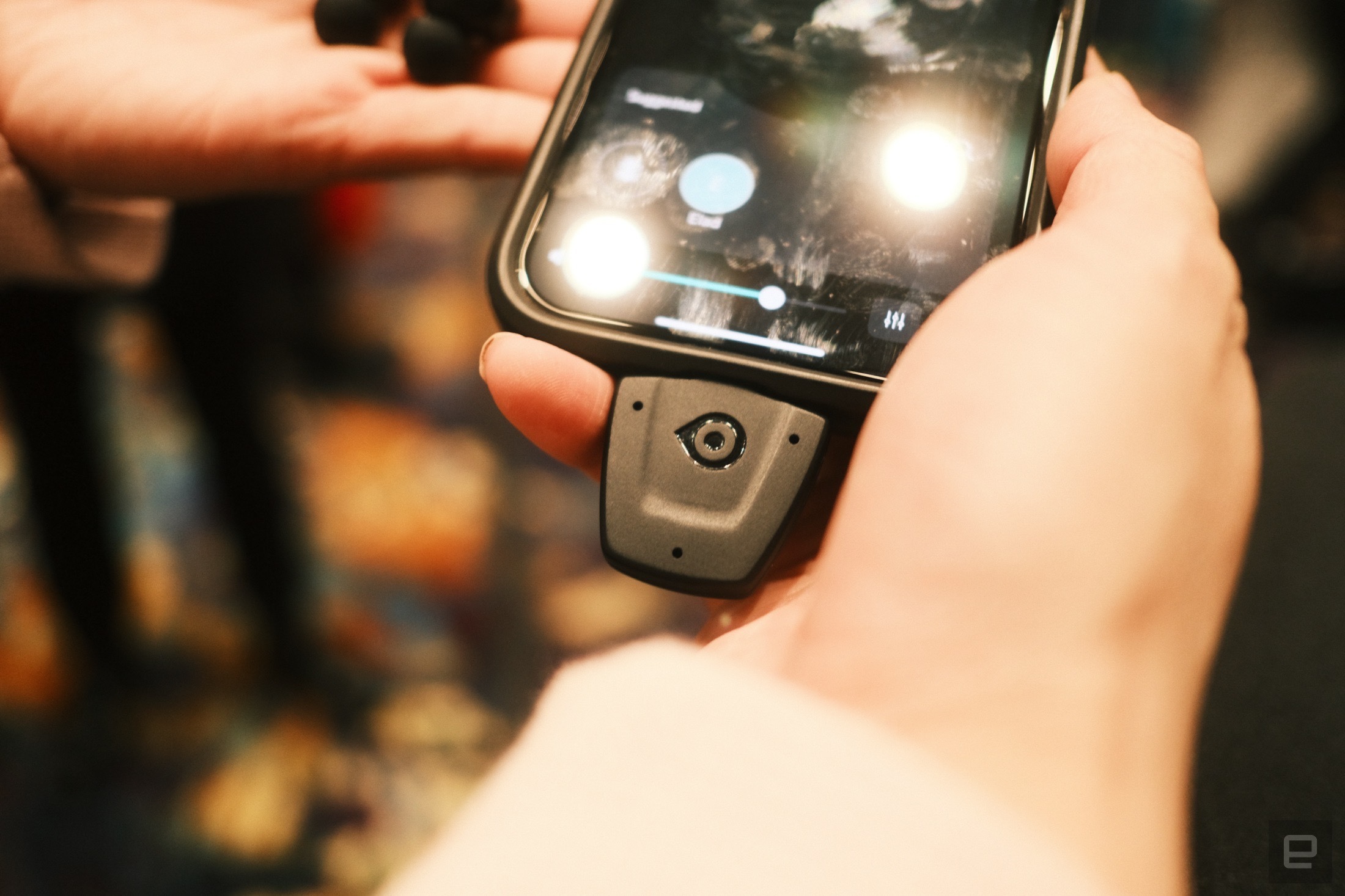 Close-up of the OrCam Hear adapter plugged into an iPhone suspended in mid-air.