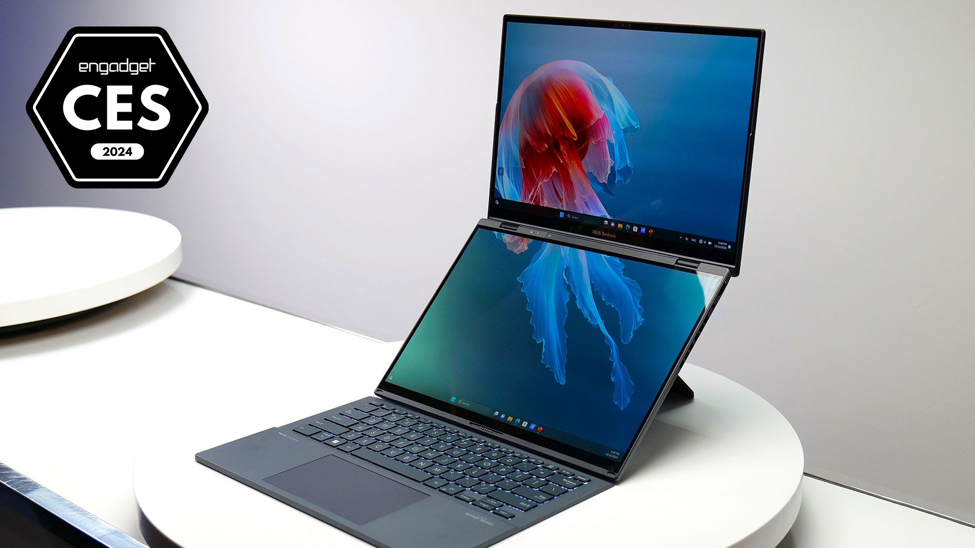 An image with a badge for Engadget Best of CES 2024 showing the product: ASUS ZenBook Duo laptop with a dual monitor on top of the normal laptop version on a white display table at the event.