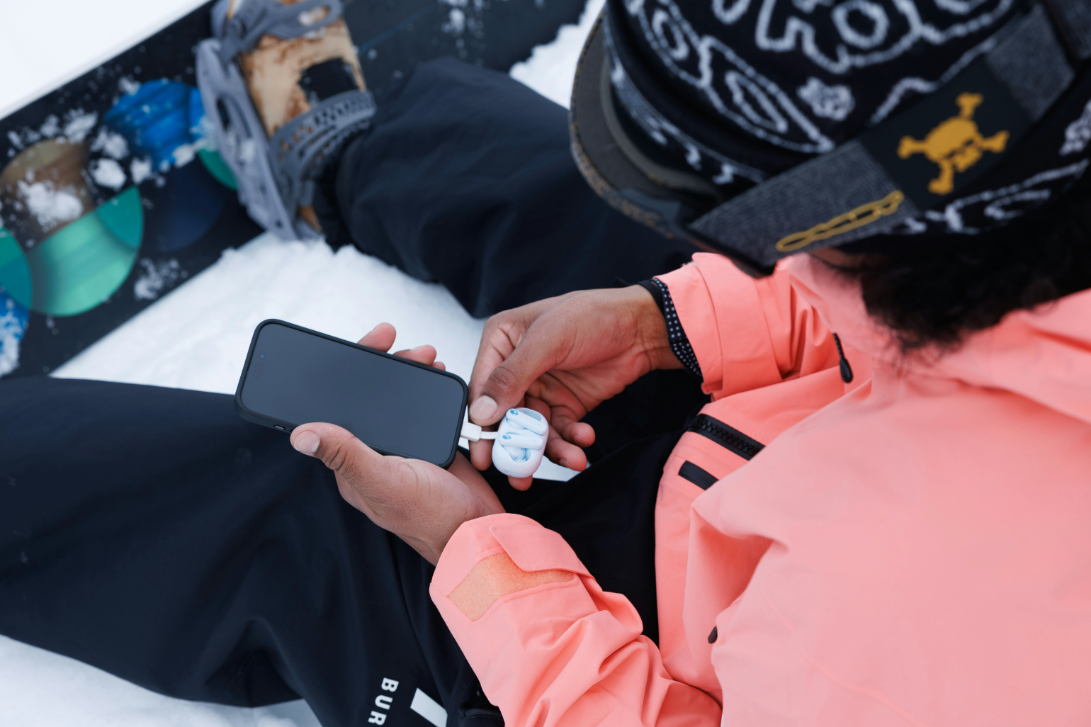 Earbuds plugging into a smartphone to charge.