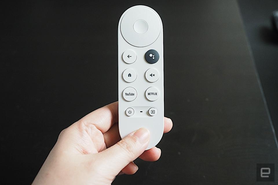 Voice remote for the Chromecast with Google TV (HD) remote. A persons hand holds the white-colored remote against a dark background.