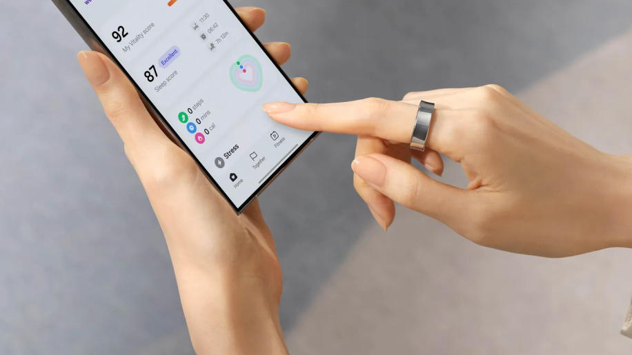 A person wearing the Galaxy Ring wearable on their right hand as they hold a phone with their left.