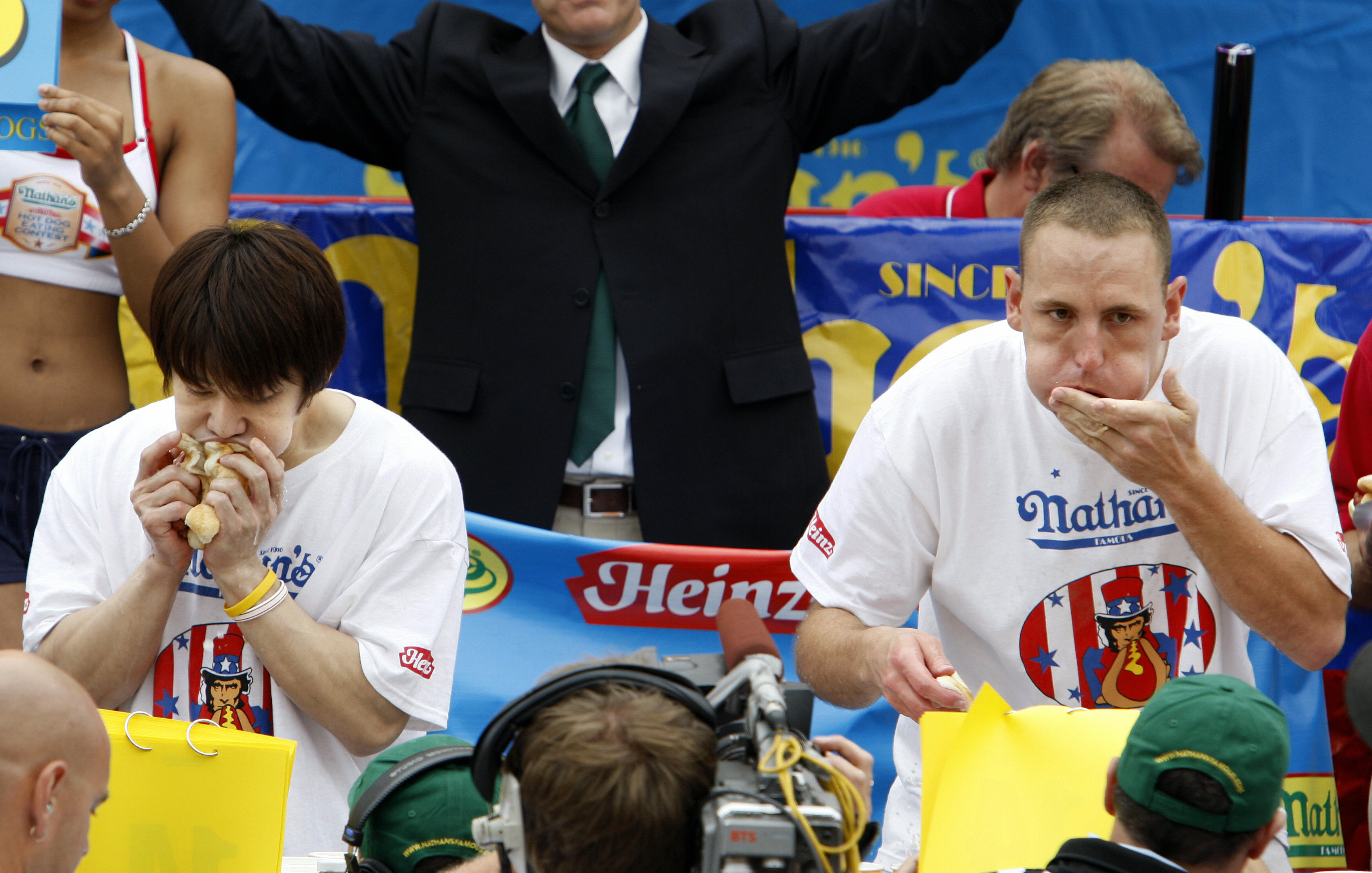 Brooklyn, UNITED STATES: Takeru Kobayashi (L) of Nagano, Japan and Joey Chestnut (R) of San Jose, California compete in the annual International July Fourth Hot Dog Eating Contest, 04 July 2007, at the original Nathan?s Famous restaurant in the Coney Island section of Brooklyn, NY. Chestnut won by eating 66 hot dogs in 12 minutes, a world record, beating defending and six-time champion Kobayashi.  AFP PHOTO/Stan HONDA (Photo credit should read STAN HONDA/AFP via Getty Images)