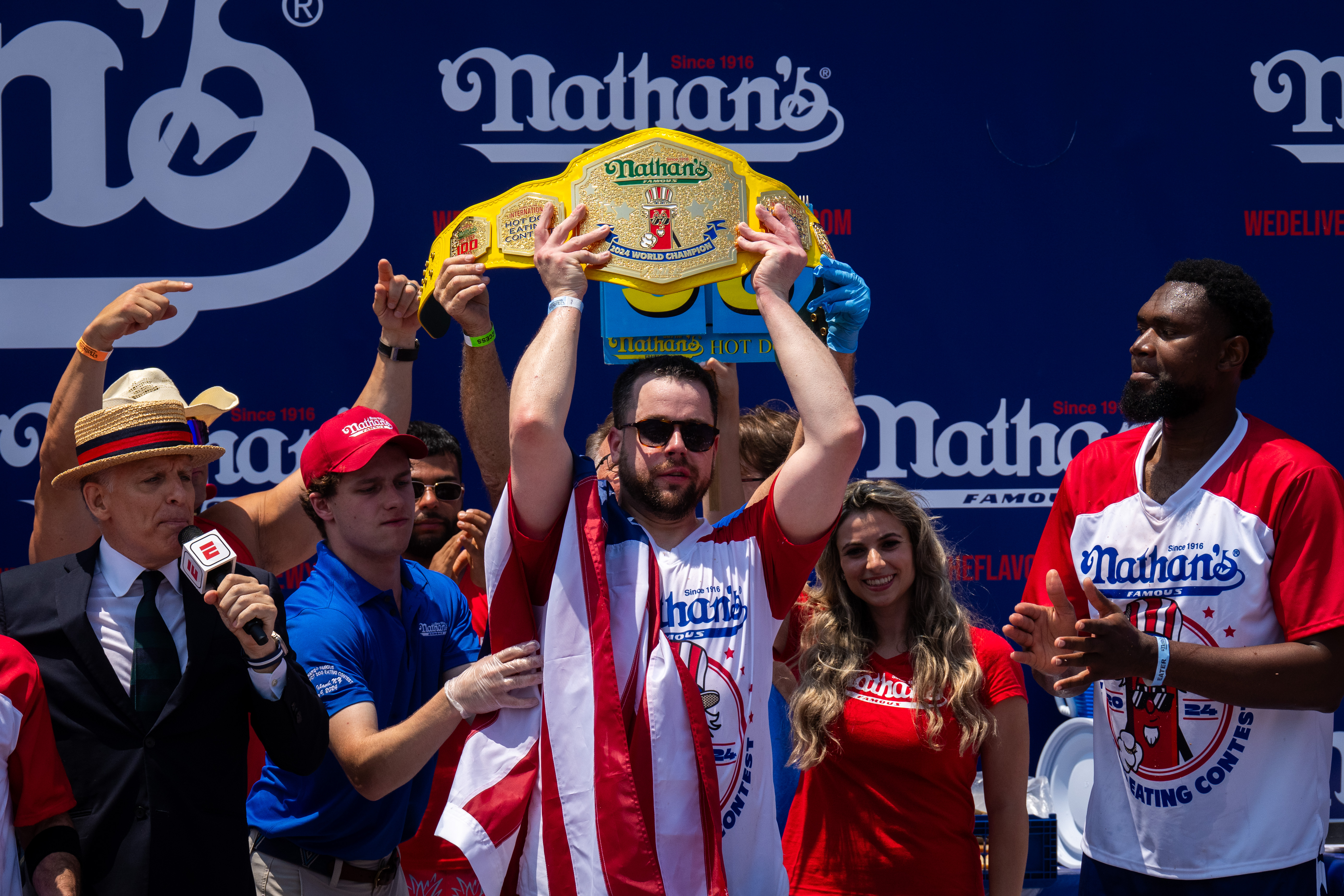 NEW YORK, NEW YORK - JULY 4: Patrick Bertoletti wins the mens title with 58 hotdogs at Nathan's Annual Hot Dog Eating Contest on July 4, 2024 in New York City. Sixteen-time winner Joey Chestnut is banned from this year's contest due to his partnership with Nathan's competitor Impossible Foods, which sells plant-based hot dogs. (Photo by Adam Gray/Getty Images)