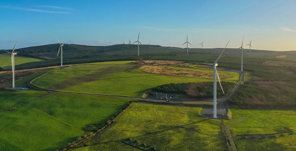 Green plains filled with large windmills. Blue sky.