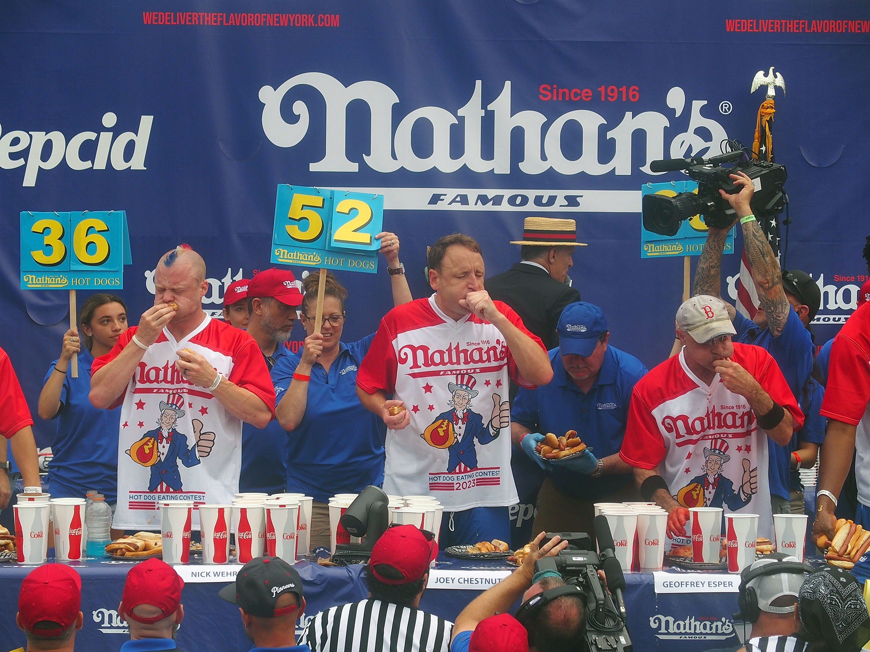 NEW YORK, NY - JULY 04:  Defending champion Joey Chestnut (C) competes in the 2023 Nathan's Famous International Hot Dog Eating Contest at Coney Island on July 4, 2023 in New York City.  (Photo by Bobby Bank/Getty Images)