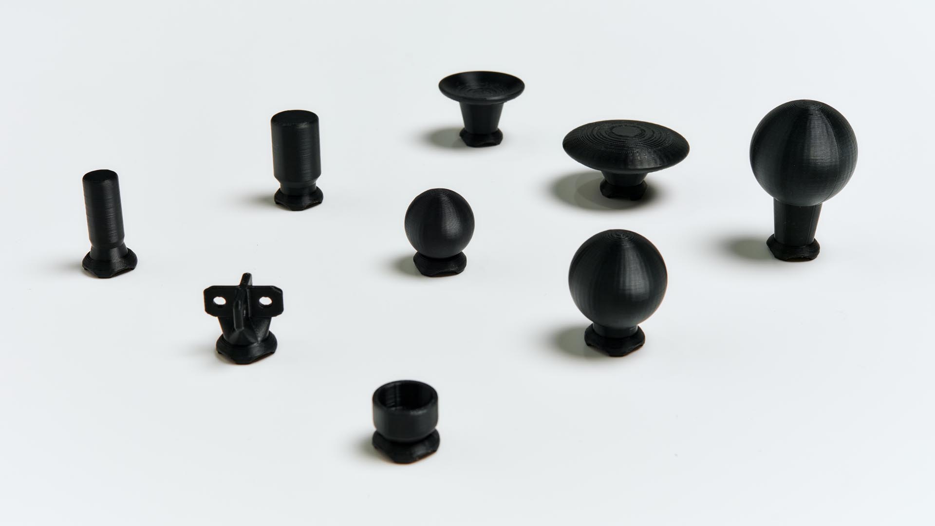 Nine black thumbstick toppers on an off-white surface.