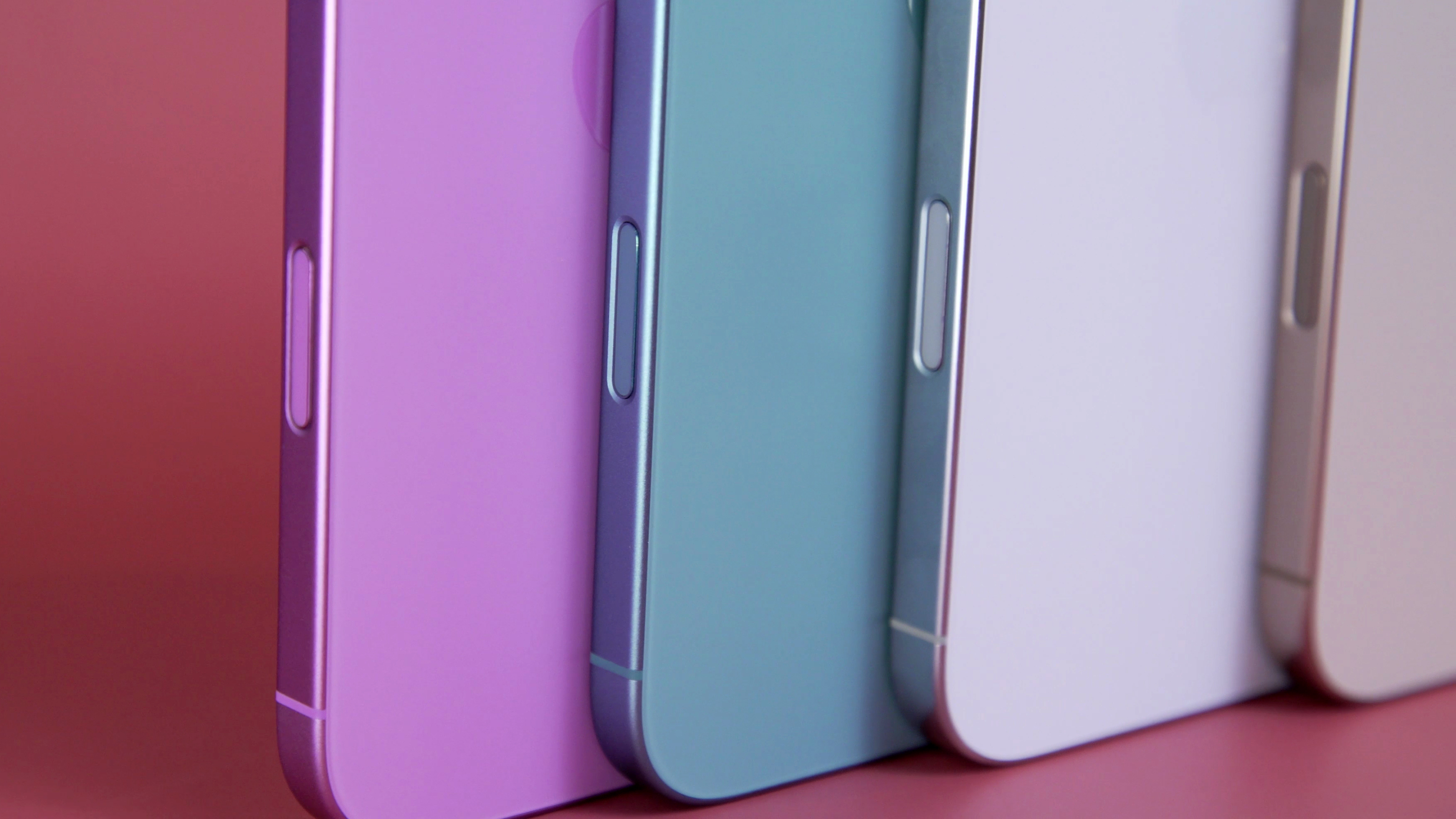 Close up shots of the bottom half of the iPhone 16 lineup, featuring from left to right a pink, teal, white and gold phones. 