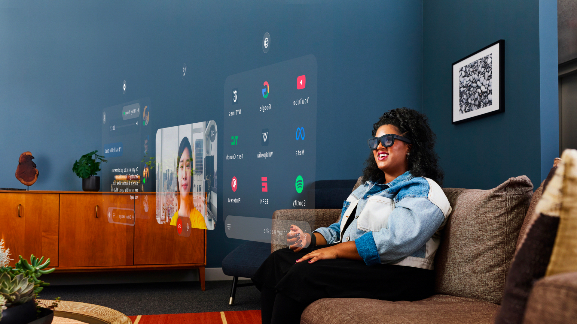 A person wearing Meta's Orion AR smart glasses and looking at a holographic overlay of a video call and apps.